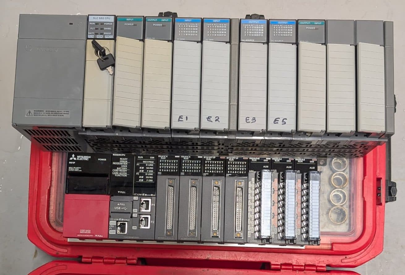 An obsolete Allen Bradley SLC 5/03 rack sitting above its replacement Mitsubishi iQ-R rack